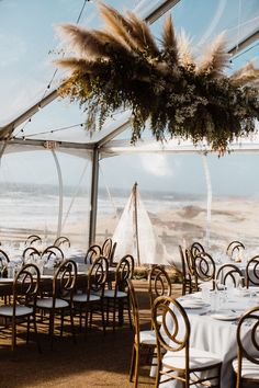 tables and chairs are set up for an outdoor wedding reception at the beach with white linens and pamodia