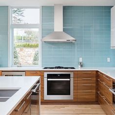 a kitchen with blue tiles and wooden cabinets