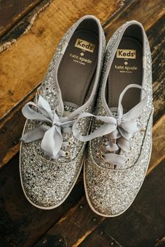 a pair of silver glittered shoes with bows on the top and bottom, sitting on a wooden floor