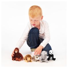 a young boy playing with stuffed animals on the floor in front of white background,