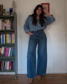 a woman standing in front of a bookshelf with her hands on her hips