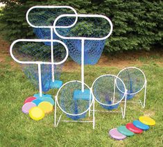 several different colored frisbees are on the grass near a metal rack with four discs