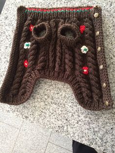 there is a knitted sweater with buttons on the front and bottom, along with two holes in the middle