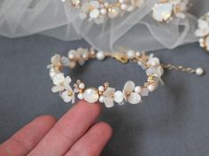 a close up of a person wearing a wedding bracelet with pearls and flowers on it