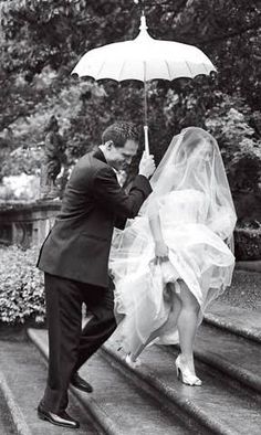 a bride and groom walking down the steps under an umbrella