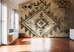 a room with wood floors and a large wall mural on the wall that has geometric designs