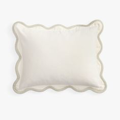 a white pillow with scalloped edges on a white background, the back side has an embroidered edge