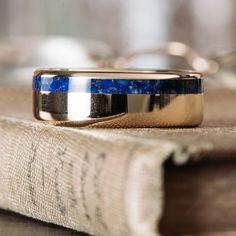 a close up of a wedding band on top of a book with a blue stone in the center