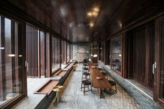 a long wooden table sitting in the middle of a room with lots of windows on both sides