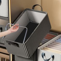 a woman is holding a black and white box with compartments in it next to some drawers