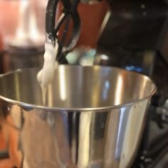 a large metal bowl on top of a stove with a black handle and white liquid pouring into it