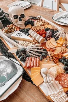 an assortment of cheeses, crackers and meats on a table with a skull