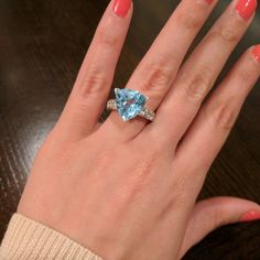 a woman's hand with a ring on it and a blue stone in the middle