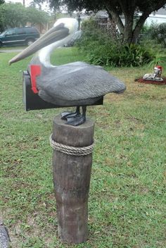 a statue of a pelican is on top of a post in the grass