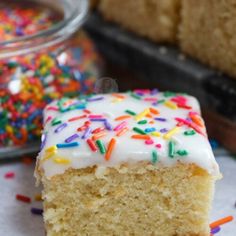 a piece of cake with white frosting and sprinkles