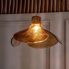 a gold colored light hanging from a ceiling in a room with white walls and wood paneling