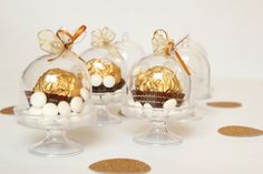 three clear glass vases with gold and white candies in them