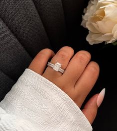 a woman's hand with a ring on it and a flower in the background