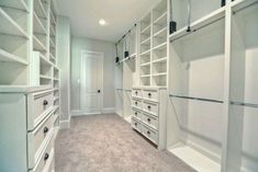 an empty walk - in closet with white shelves and drawers, carpeted flooring