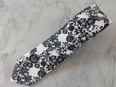 Upgrade your wardrobe in style with our handmade white and black floral pattern tie. This stunning cotton tie is guaranteed to enhance any outfit. Perfect gift for him. Black Ties With Design, Spring Cotton Ties For Black Tie Events, White Cotton Ties For Gifts, White Cotton Ties For Formal Occasions, Black Ties For Spring, Elegant Cotton Ties For Gifts, Black Tie For Spring, Cotton Ties For Black Tie Events In Summer, Cotton Ties For Black Tie Occasions In Summer