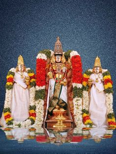 an idol is displayed in front of flowers and garlands on the stage with other statues