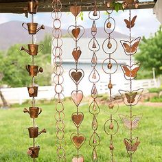 a wind chime hanging from the side of a wooden structure in a yard with grass and trees