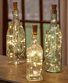 three bottles with lights in them sitting on a table