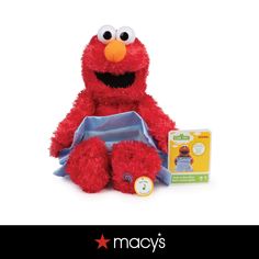 a red stuffed animal sitting next to a box with a tag on it's chest