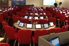 rows of tables and chairs with electronic devices on them in a conference room, ready to be used