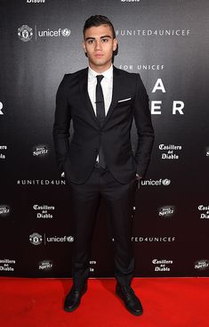 a man in a suit and tie standing on a red carpet