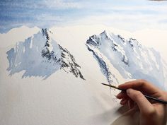 someone is painting a mountain scene with watercolors