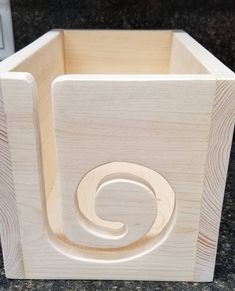 a close up of a wooden box on a granite counter top with the letter c carved into it