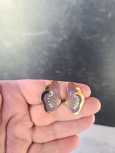 These are a vintage pair of Laurel Burch peony stud earrings.  Hallmarks: Laurel Burch  Weighs: 5 grams  .75" tall and 1 1/16" wide  All measurements are approximate.  Condition: Good vintage condition. Normal wear associated age. A few light surface scratches and slight discoloration. Please see photos. Sold as is. Priced accordingly.  Please look over carefully and inspect any and all photos. Our shop is committed to fully disclosing all items' conditions and history with as great of detail as Vintage Flower-shaped Pierced Jewelry, Purple Clip-on Jewelry Gift, Purple Clip-on Jewelry For Gifts, Purple Clip-on Jewelry For Gift, Purple Clip-on Jewelry As Gift, Purple Clip-on Jewelry As A Gift, Vintage Enamel Flower Earrings, Vintage Gold Flower Earrings With Enamel, Enamel Clip-on Earrings As Gift