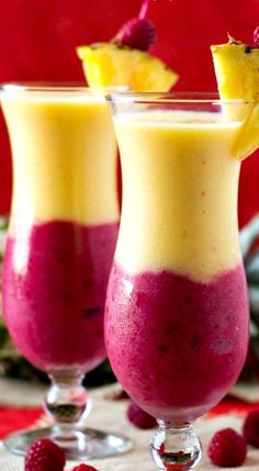 two glasses filled with fruit and ice cream on top of a red table cloth next to pine