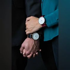 two people are holding hands while wearing wristwatchs and black suits with blue jackets