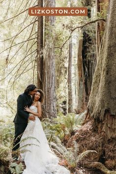 a bride and groom standing in the woods with their arms around each other, embracing