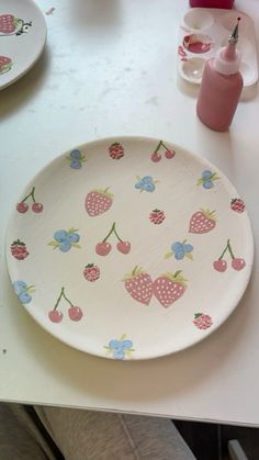 a plate with cherries and polka dots on it sitting on a table next to other plates