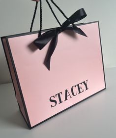 a pink shopping bag with a black bow hanging from it's handle and the word stagey written on it