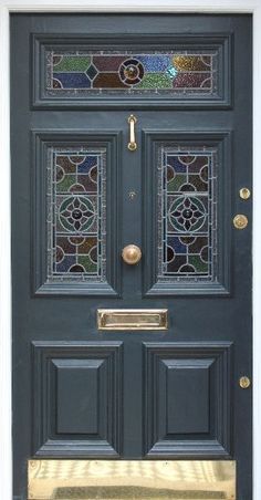 the front door is painted dark blue and has stained glass panels on it, along with gold trim