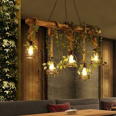 an indoor restaurant with plants growing on the wall and hanging lights over the tables in front of it