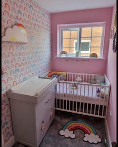 a baby's room decorated in pastel colors with rainbow wallpaper and crib