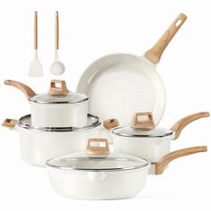 a set of white pots and pans with wooden handles