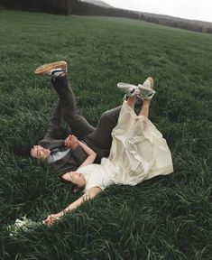 a man and woman laying in the grass with their feet on each others'heads