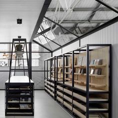 an empty room with shelves and ladders full of books on the wall, in front of a large window