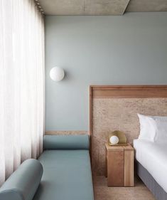 a room with a bed, couch and lamp on the wall next to each other