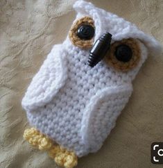 a crocheted owl cell phone case on a bed