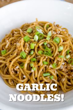 a white bowl filled with noodles and topped with scallions, green onions and sesame seeds