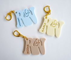 three personalized key chains are shown on a white surface, one has an elephant and the other is a dog