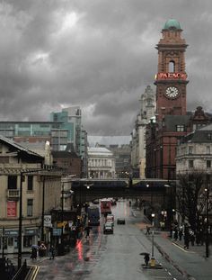 a large clock tower towering over a city filled with tall buildings and people walking down the street