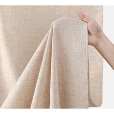 a hand is holding up the curtain to reveal it's natural linen fabric material